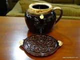 (R3) JAR AND TRIVET; 2 PC LOT OF DARK BROWN STONEWARE TO INCLUDE A JAR WITH A HANDLE AND A