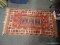 (LEFT WALL) ORIENTAL RUG; HAND WOVEN ORIENTAL RUG IN RED, BLUE AND IVORY GEOMETRIC PATTERNS- 27 IN X