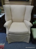 (LEFT WALL) WING CHAIR; MAHOGANY WING CHAIR WITH BEIGE UPHOLSTERY- 33 IN X 35 IN X 40 IN UPHOLSTERY