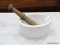 (TABLES) LARGE ACID PROOF MORTAR WITH WOODEN PESTLE. WHITE MORTAR HAS A LIP AND MEASURES 4