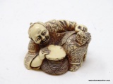 (RFRT) SCRIMSHAW FIGURINE; HAND CARVED FIGURINE OF A LAYING ORIENTAL MAN PLAYING THE DRUMS WITH A