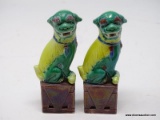 (RFRT) PAIR OF PORCELAIN FOO DOGS; 2 PIECE SET OF YELLOW AND GREEN FOO DOGS SITTING ON A MAROON