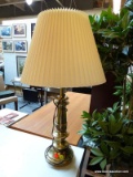 (R1) BRASS TABLE LAMP; TURNED, POLISHED BRASS TABLE LAMP WITH A REEDED, IVORY COLORED SHADE.