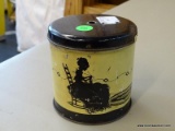 (R3) VINTAGE STRING HOLDER TIN; PALE YELLOW AND BLACK TIN WITH A WOMAN KNITTING IN A ROCKING CHAIR.