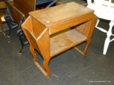 (R7) WOODEN MAGAZINE TABLE; TABLE HAS 2 SIDE POCKETS AND A LOWER SHELF. NEEDS TO BE REFINISHED AND
