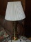 (R3) BRASS TABLE LAMP; TURNED, POLISHED BRASS TABLE LAMP WITH A REEDED, IVORY COLORED SHADE.