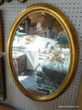 (WALL) OVAL MIRROR; WALL HANGING, BEVELED GLASS MIRROR SITTING IN A GOLD TONED FRAME. MEASURES 23