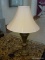 (R1) TABLE LAMP; CHAMPAGNE FINISH, COMPOSITE TABLE LAMP WITH A CREAM BELL SHAPED SHADE. MEASURES 30