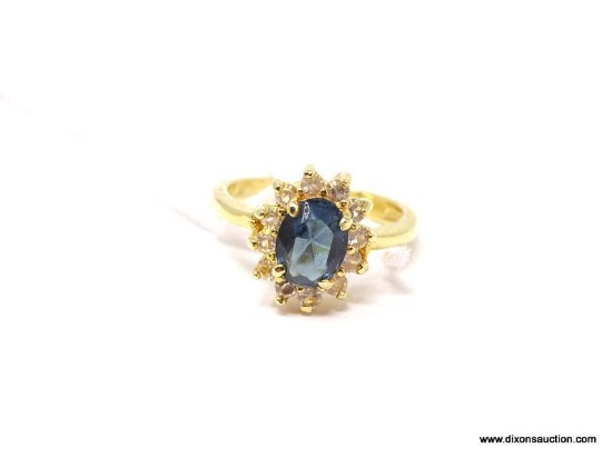 GOLD TONE STATEMENT RING WITH A CENTER SET SAPPHIRE STONE SURROUNDED BY CZ GEMSTONES. APPROX. SIZE