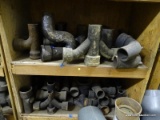 (2) SHELF LOTS OF CAST IRON PIPE FITTINGS. VARIOUS DIFFERENT TYPES.