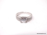 .925 STERLING SILVER RING WITH LARGE PRINCESS CUT CZ ACCOMPANIED BY SMALLER CZ STONES ON EACH SIDE.