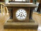 MANTLE CLOCK; VINTAGE MANTLE CLOCK WITH BRASS INNER WORKINGS, A PORCEALIN FACE AND PINE CASE. NEEDS