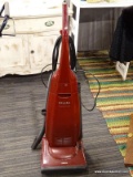 MIELE VACUUM CLEANER; BURGUNDY IN COLOR AND INCLUDES ATTACHMENTS.