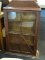 ANTIQUE FLOOR STANDING DISPLAY CABINET WITH 3 INTERIOR SHELVES AND A SINGLE GLASS PANELED DOOR.