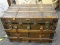 ANTIQUE STEAMER TRUNK WITH METAL HARDWARE AND LEATHER STRAPPING. MEASURES 32 IN X 20 IN X 23 IN.