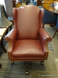BURGUNDY UPHOLSTERED OFFICE ARM CHAIR WITH BRASS STUDDING AND MAHOGANY BASE. MEASURES 29 IN X 34 IN