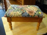 FOOT STOOL WITH INTERIOR STORAGE. HAS A FLORAL UPHOLSTERED LIFT-LID TOP AND TURNED LEGS. MEASURES 15