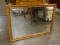 FRAMED MIRROR WITH A WOODEN FRAME WITH GOLD TONED ACCENTS ON THE EDGES. MEASURES 33 IN X 22.5 IN.