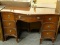 MAHOGANY 7 DRAWER KNEE HOLE DESK WITH ROUND BRASS PULLS AND A BOW FRONT. MEASURES 46 IN X 20 IN X 30