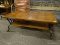 OAK AND METAL COFFEE TABLE WITH 1 LOWER SHELF. MEASURES 50 IN X 28 IN X 19 IN. ITEM IS SOLD AS IS