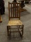 VINTAGE MAHOGANY AND WOVEN WICKER SEAT ROCKING CHAIR WITH SLAT BACK. MEASURES 17 IN X 29 IN X 34 IN.