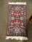 SMALL AREA RUG IN HUES OF BURGUNDY, GREEN, AND BLUE. MEASURES 2 FT 8 IN X 3 FT 2 IN. ITEM IS SOLD AS