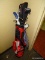 LOT OF GOLF CLUBS WITH RED AND WHITE CARRIER. SOME CLUBS HAVE SOCK STYLE COVERS. APPROXIMATE TOTAL