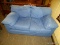 BLUE DENIM UPHOLSTERED LOVESEAT WITH REMOVABLE SEAT CUSHIONS. MEASURES 57 IN X 33 IN X 28 IN. ITEM