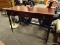 MAHOGANY FINISH 3 DRAWER DESK WITH REEDED COLUMN LEGS. MEASURES 48 IN X 21 IN X 29.5 IN. 1 LEG NEEDS