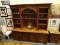 MAHOGANY BOOKCASE WITH 8 SHELVES AND CROWN MOLDING ON THE TOP HALF AND 4 DOORS WITH BRASS PULLS.