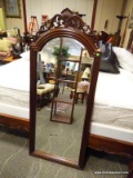 HIGHLY CARVED SOLID MAHOGANY FRAMED WALL MIRROR WITH BEVELED GLASS EDGE. MEASURES 26.5 IN X 63.5 IN.