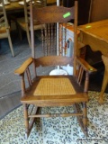 VINTAGE PRESSED AND SPINDLE BACK CANE BOTTOM ROCKING ARMCHAIR. MEASURES 26 IN X 34 IN X 42 IN. ITEM