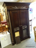 MAHOGANY FINISH 2 DOOR ARMOIRE WITH A SUN CARVED TOP, TWIST CARVED COLUMN CORNERS, CARVED FRONT