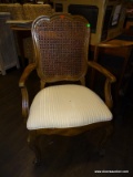 FRENCH PROVINCIAL DINING ARM CHAIR WITH CREAM STRIPED UPHOLSTERY AND A CANE BACK. MEASURES 23 IN X