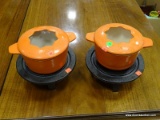 PAIR OF RACHEL RAY CAST IRON AND ENAMELED COOKING POTS WITH CAST IRON STANDS AND HEATERS. EACH HAS A