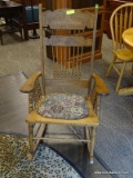 ANTIQUE OAK PRESSED AND SPINDLE BACK ROCKING ARM CHAIR WITH GEOMETRIC PATTERN UPHOLSTERED SEAT.