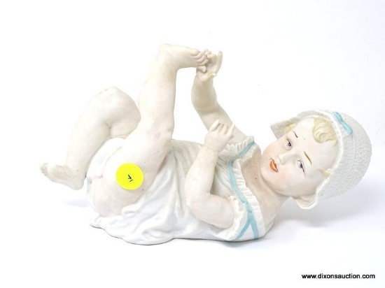 FIGURINE OF A BABY LAYING ON HER BACK PLAYING WITH HER TOES. MEASURES 9 IN X 5 IN. IS MISSING THE