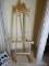 (DR) GOLD GILT AND PAINTED EASEL- 25 IN X 72 IN, ITEM IS SOLD AS IS WHERE IS WITH NO GUARANTEES OR