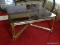 (FAM) GOLD AND SMOKED GLASS TOP COFFEE TABLE- 36 IN X 36 IN X 15 IN, ITEM IS SOLD AS IS WHERE IS