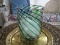 (SUN) CLEAR AND GREEN SWIRL PATTERN VASE WITH FOOTED BASE. MEASURES 8.5 IN X 12 IN. ITEM IS SOLD AS