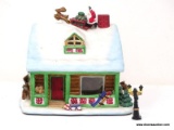 HOLIDAY VILLAGE BUILDING IN THE FORM OF A HOME WITH SANTA LANDING ATOP THE ROOF. ITEM IS SOLD AS IS
