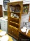 (R1) PINE CORNER CABINET WITH 3 UPPER SHELVES AND 2 LOWER DOORS THAT OPEN TO REVEAL EXTRA SHELVING.