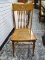 (R1) SOLID OAK SIDE CHAIR WITH CANE BOTTOM SEAT AND SPINDLE BACK. MEASURES 17 IN X 19 IN X 39 IN.