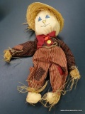 (R1) CLOTH STUFFED TOY SCARECROW WITH STRIPED PANTS AND A BURGUNDY BOW TIE. ITEM IS SOLD AS IS WHERE