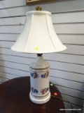 (R2) PORCELAIN FLORAL THEMED LAMP WITH CLOTH BELL SHAPED SHADE AND A GOLD TONE FINIAL. MEASURES 23