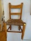 (UPHALL) ANTIQUE OAK CHILD'S CHAIR WITH RUSH BOTTOM SEAT. MEASURES 14 IN X 12 IN X 28 IN. ITEM IS