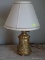 (UPBED 2) GOLD PAINTED METAL TABLE LAMP WITH CLOTH SHADE. MEASURES 18 IN TALL. ITEM IS SOLD AS IS