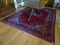 (DR) HAND WOVEN FLORAL PATTERN AREA RUG IN HUES OF RED, BLUE, CREAM, AND BLACK. MEASURES 8 FT 1 IN X