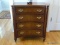 (DR) MAHOGANY 4 DRAWER CHEST WITH BRASS CHIPPENDALE PULLS AND REEDED COLUMN CORNERS. MEASURES 26 IN