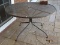 (OUT) CAST IRON AND MESHED WIRE PATIO TABLE. MEASURES 43 IN X 26 IN. ITEM IS SOLD AS IS WHERE IS